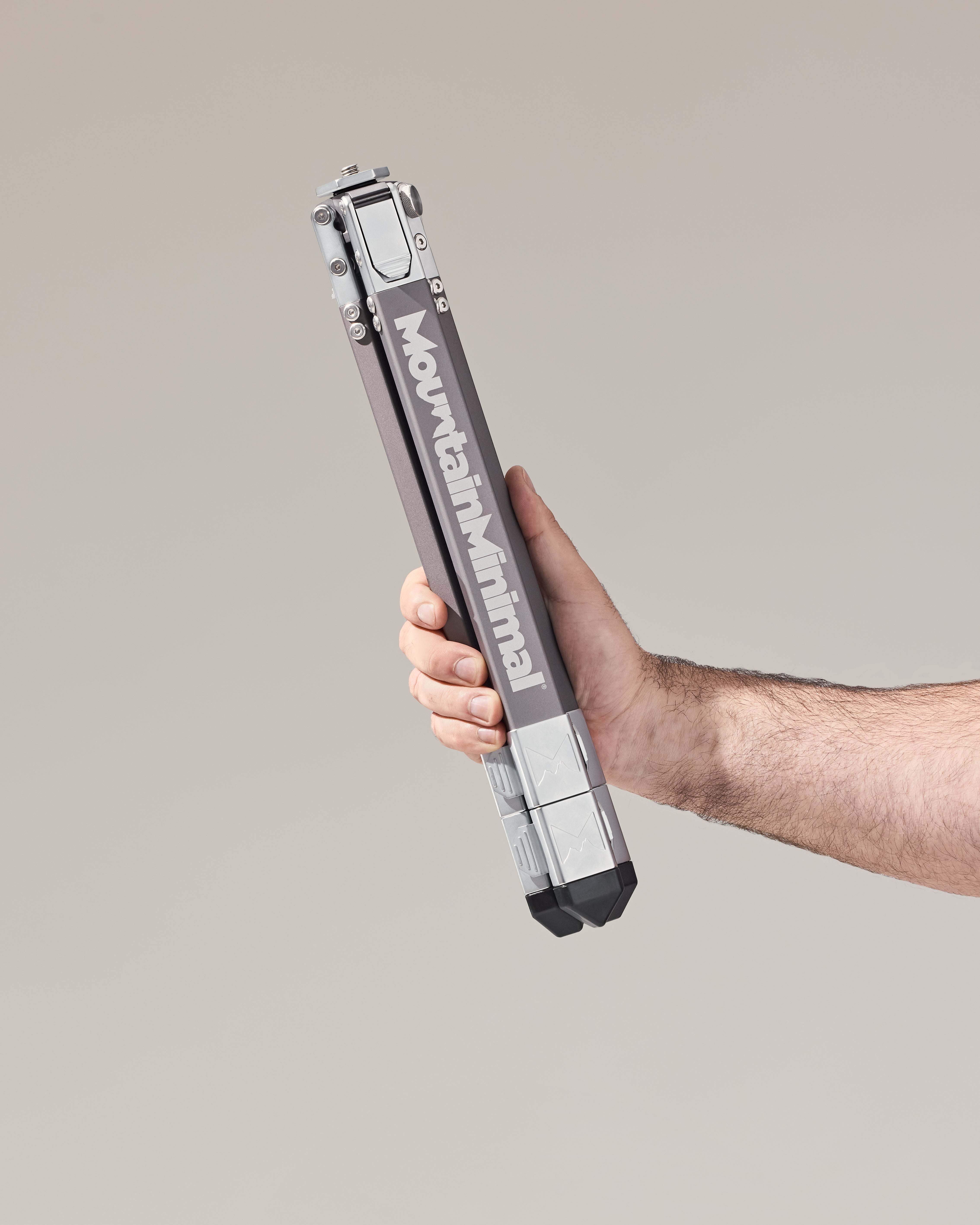 Hand holds a collapsed Mountain Minimal™ Scree™ 37 tripod, showing how small it is.